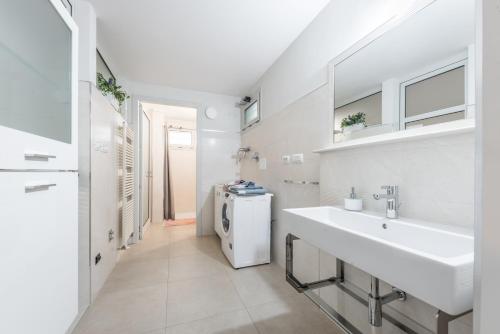 a white bathroom with a sink and a refrigerator at La Dimora nel Parco in Modena