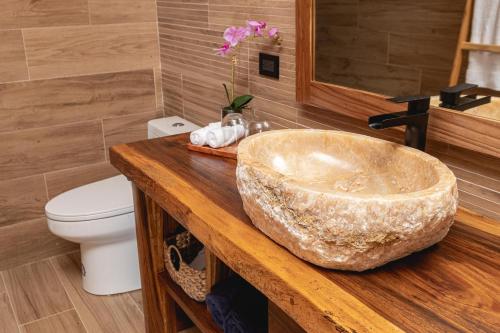 La salle de bains est pourvue d'un grand lavabo en marbre et de toilettes. dans l'établissement Lamangata Luxury Surf Resort, à Dominical