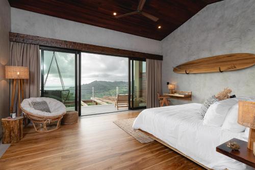 une chambre avec un grand lit et une grande fenêtre dans l'établissement Lamangata Luxury Surf Resort, à Dominical
