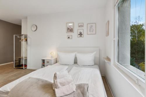 a white bedroom with a white bed and a window at Vorstadtoase für 2 - Netflix, Parkplatz, Nähe BER, Queensize-Bett in Eichwalde