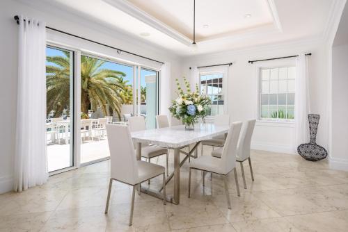 a white dining room with a table and chairs at Salt Life Villa in Long Bay Hills