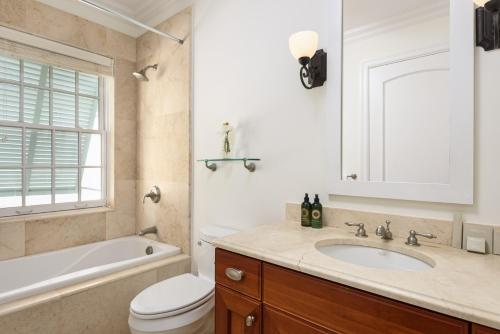a bathroom with a sink and a tub and a toilet at Salt Life Villa in Long Bay Hills