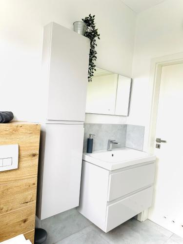 a white bathroom with a sink and a mirror at Coast House 25 -BALTIC GARDEN TRZĘSACZ in Trzęsacz