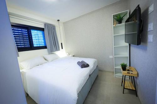 - une chambre avec un grand lit blanc et une télévision dans l'établissement Betsalel accommodation, à Jérusalem