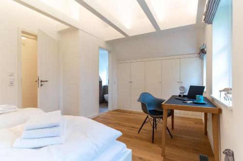 a bedroom with a bed and a desk with a laptop at Reetdachhaus-Hoher-Himmel in Sankt Peter-Ording