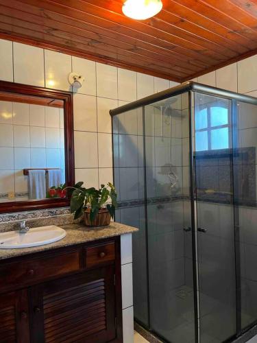 uma casa de banho com uma cabina de duche em vidro e um lavatório. em Casa Canto da Serra em Búzios
