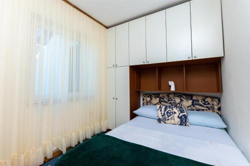 a small bedroom with a bed and a window at Apartment VESNA in Pinezici