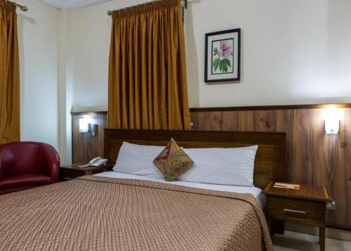 アクラにあるCharleston Hotelのベッドと赤い椅子が備わるホテルルームです。