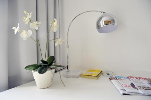 a white table with a vase and a plant on it at Cityhotel am Thielenplatz in Hannover
