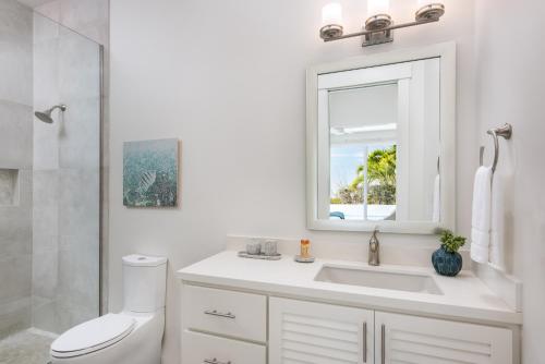 La salle de bains blanche est pourvue d'un lavabo et d'un miroir. dans l'établissement Salt Air and Second Wind, à Long Bay Hills