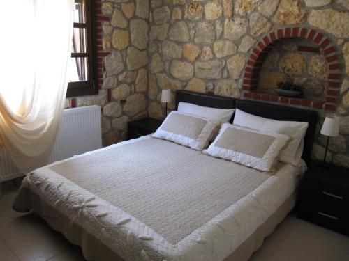 a bedroom with a large bed with a stone wall at Psakoudia Villas in Psakoudia