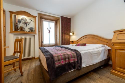 a bedroom with a bed and a chair and a window at Camana Veglia in Livigno