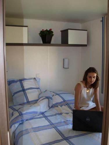 a woman sitting on a bed with a laptop at Le colvert in Orist