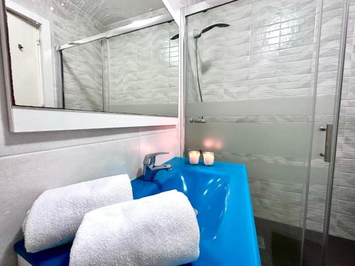 La salle de bains est pourvue d'un lavabo bleu et d'un miroir. dans l'établissement Gran Apartamento en PRIMERA LINEA DE PLAYA, la cala del moral, à Cala del Moral