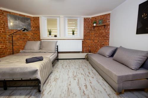 a living room with two couches and a brick wall at LOFTY CHOPINA in Bydgoszcz