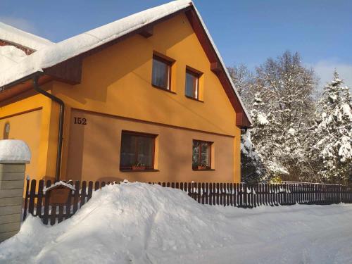 a house with a pile of snow in front of it at Ubytování Pod statkem in Tichá