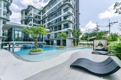 un edificio con piscina en frente de un edificio en Toppmodern lägenhet i Bang Saray, en Bang Sare