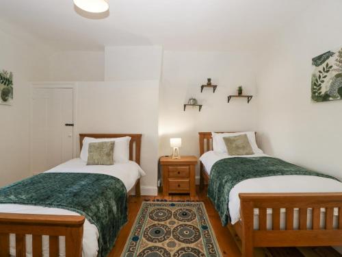 a bedroom with two beds and a rug at Builth House in Abergavenny