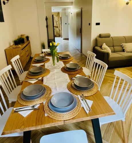 a wooden table with chairs and plates on it at GÓRSKA CISZA - Duży, komfortowy, wyjątkowy Apartament in Stronie Śląskie