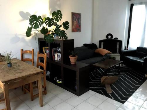 a living room with a black couch and a table at Pavillon avec cour privée in Bagnolet