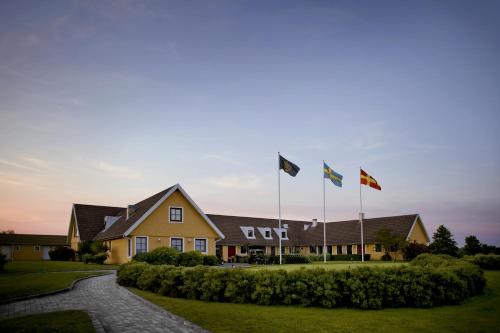 a group of flags flying in front of a house at Bjäre Golfklubb Hotel & Lodge in Båstad