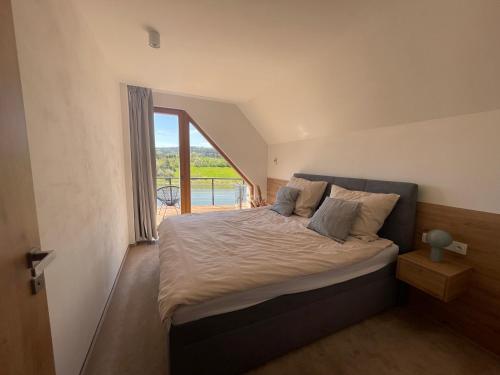 a bedroom with a large bed with a large window at Dům nad přehradou s bazénem in Lazinov