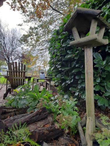 a bird house and a bench in a garden at Tuinkamer 't Strunerke in Augustinusga