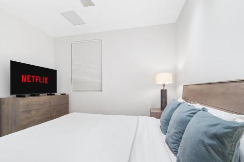 a white bedroom with a bed and a tv at O Condominium Beachfront Residences, by Bocobay Aruba in Palm-Eagle Beach