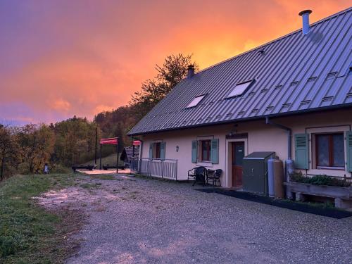a house with a sunset in the sky behind it at Auberge du Graber in Dolleren
