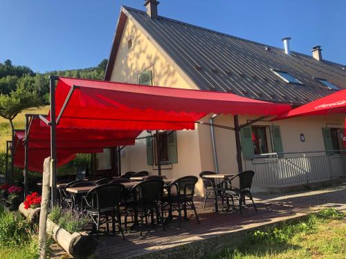 patio con tavoli e sedie sotto un ombrellone rosso di Auberge du Graber a Dolleren
