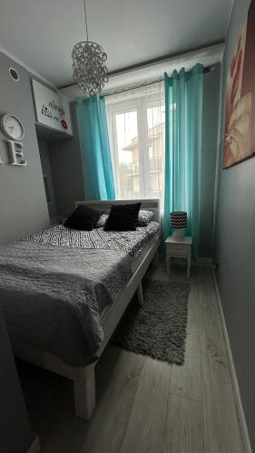 a bedroom with a bed with blue curtains and a window at Apartamenty Deluxe NADIA II - Centrum in Zielona Góra