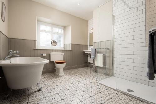 a bathroom with a tub and a toilet and a sink at Overview Cottage in Belford