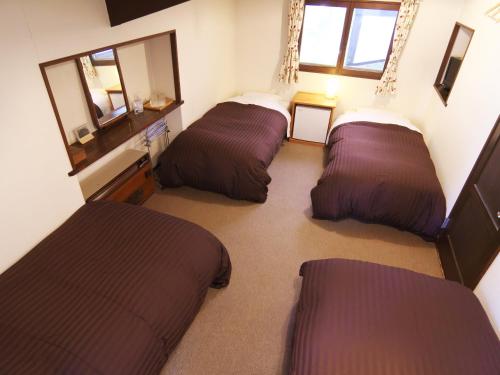 a room with three beds and a mirror at Hakuba Goryu Pension Kurumi in Hakuba
