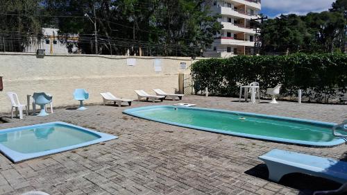 a swimming pool with chairs and a table and chairs at Aconchegante apartamento Teresópolis in Teresópolis