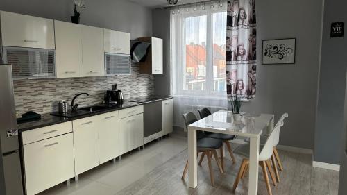 Una cocina con gabinetes blancos y una mesa con sillas. en Apartamenty SOFIJA Deluxe Centrum, en Zielona Góra