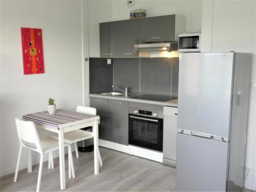 a small kitchen with a table and a refrigerator at Les rives de l'adour in Dax