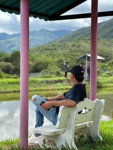 a man sitting on a bench holding a skateboard at Hotel Campestre La María Toro Valle in Toro