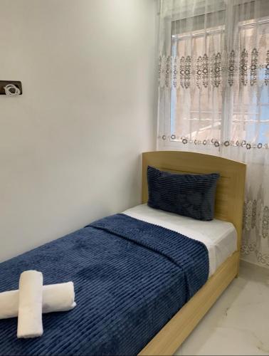 um quarto com uma cama com lençóis azuis e uma janela em Casa Yakhlef em Chefchaouen