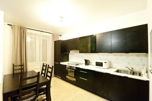a kitchen with black cabinets and a table and a microwave at City Centre Vip 202 in Tbilisi City