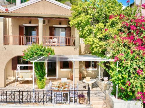 a house with a porch and a patio with flowers at Villa Tesoro Kalami with private pool by DadoVillas in Kalami
