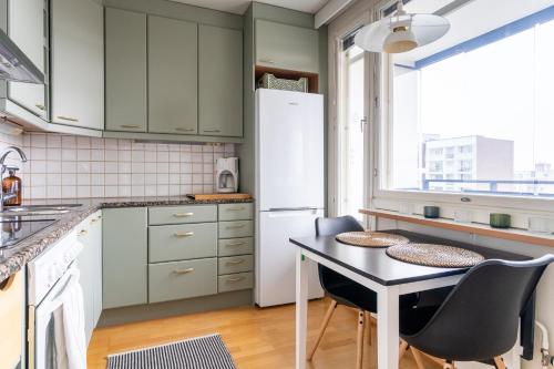 Il comprend une cuisine équipée d'une table et d'un réfrigérateur. dans l'établissement Kodikas asunto Tikkurilassa, à Vantaa
