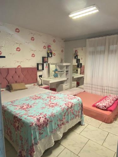 a bedroom with two beds and a wall with flowers at Tia Moni - diárias individuais in Blumenau
