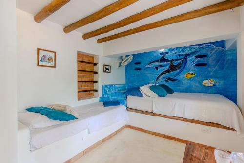 a bedroom with two beds and a painting on the wall at Casa Caracola in Tubará