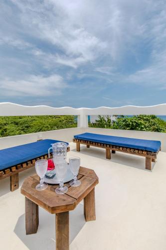 a table with wine glasses and a bench on a deck at Casa Caracola in Tubará