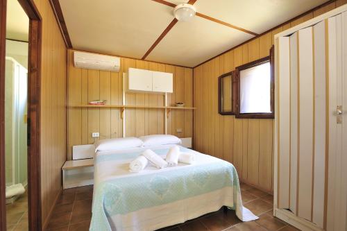 a bedroom with a bed with towels on it at Villaggio Camping Tesonis Beach in Tertenìa