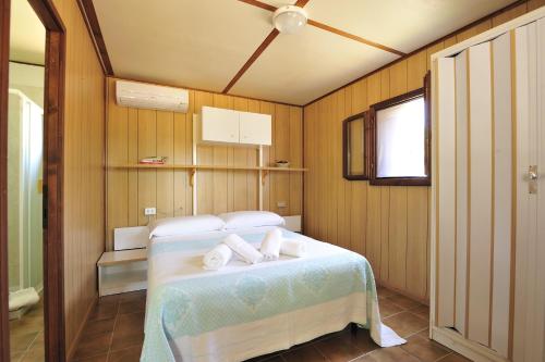 a bedroom with a bed with towels on it at Villaggio Camping Tesonis Beach in Terten&igrave;a