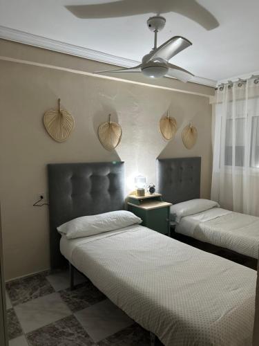 1 dormitorio con 2 camas y ventilador de techo en Apartamento centrico Venecia, en Sevilla