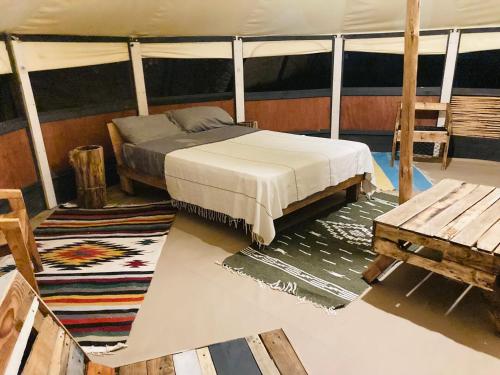 1 dormitorio con cama, mesa y banco en BCS BuenaOnda sea view 7mt bell tent, en El Sargento