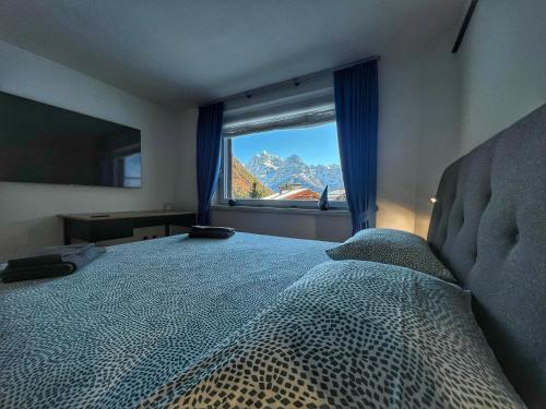 una camera da letto con un grande letto con una grande finestra di Bonapace Dolomites Apartments a Madonna di Campiglio