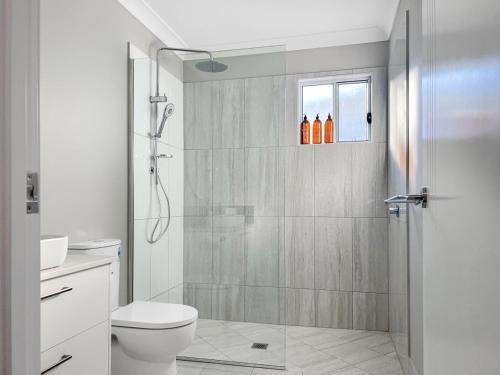 a white bathroom with a shower and a toilet at Family-friendly Seaside Gem in Urangan